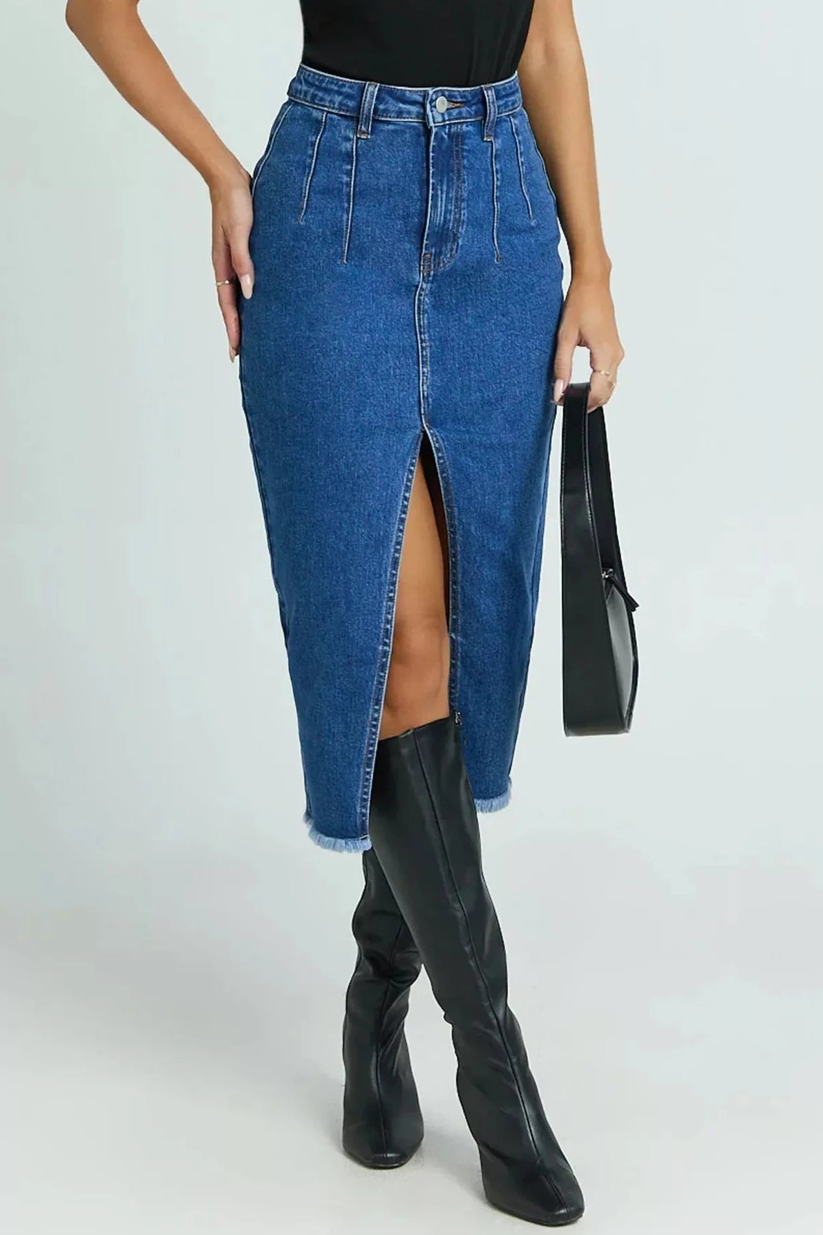 Person wearing a blue denim skirt with a high slit and black boots on a white background