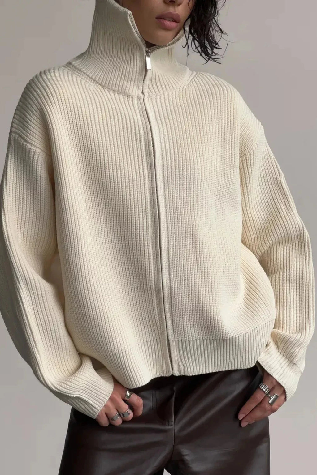 Person wearing a cream ribbed sweater against a gray background