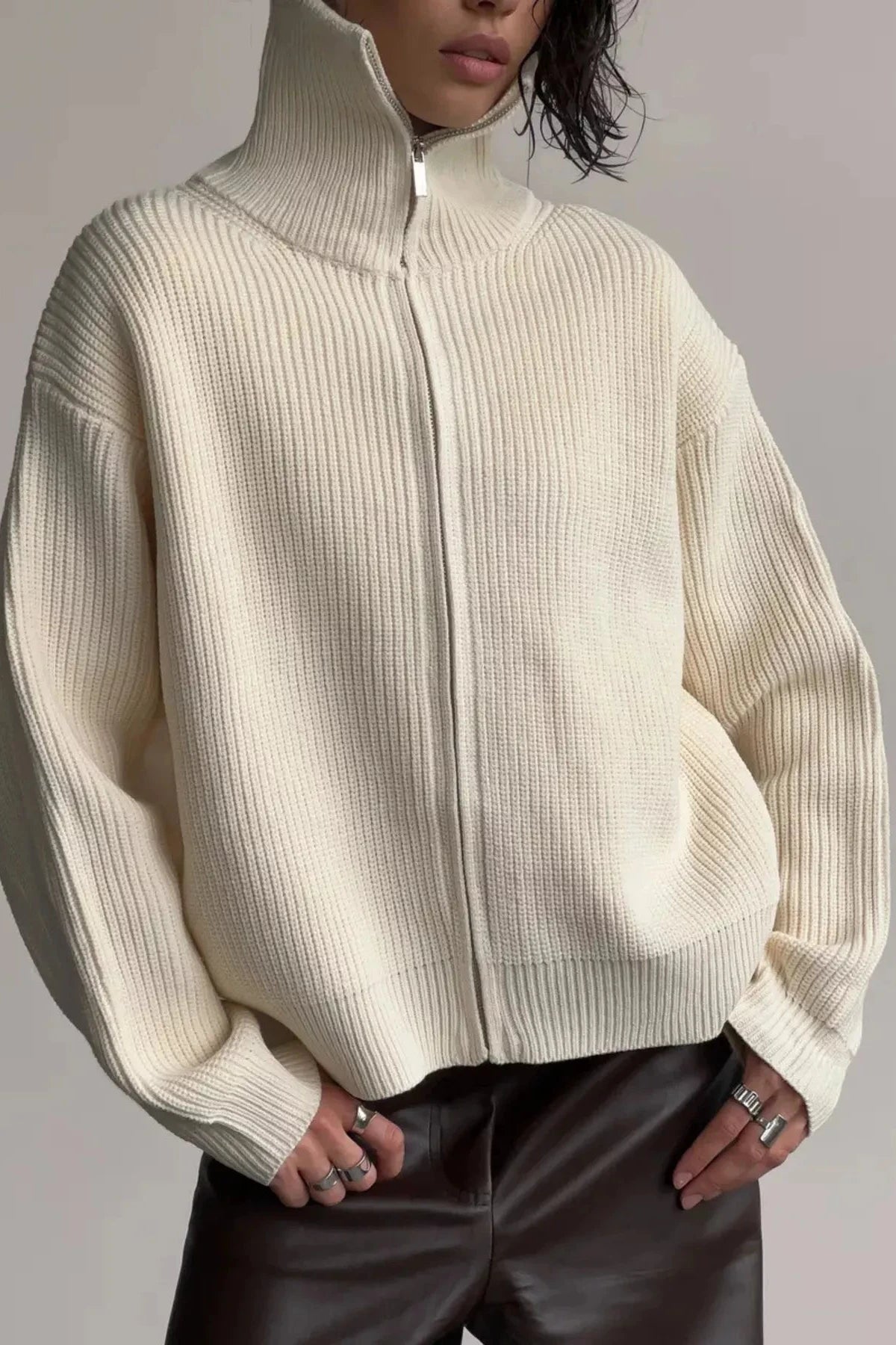 Person wearing a cream ribbed sweater against a gray background