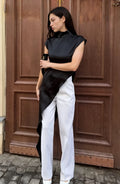 Woman wearing a black and white outfit standing in front of a wooden door.