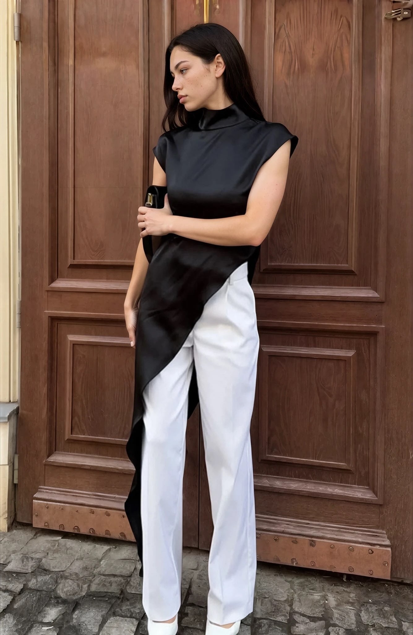 Woman wearing a black and white outfit standing in front of a wooden door.