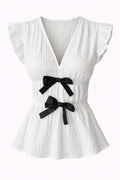 White pleated top with black bows on a white background