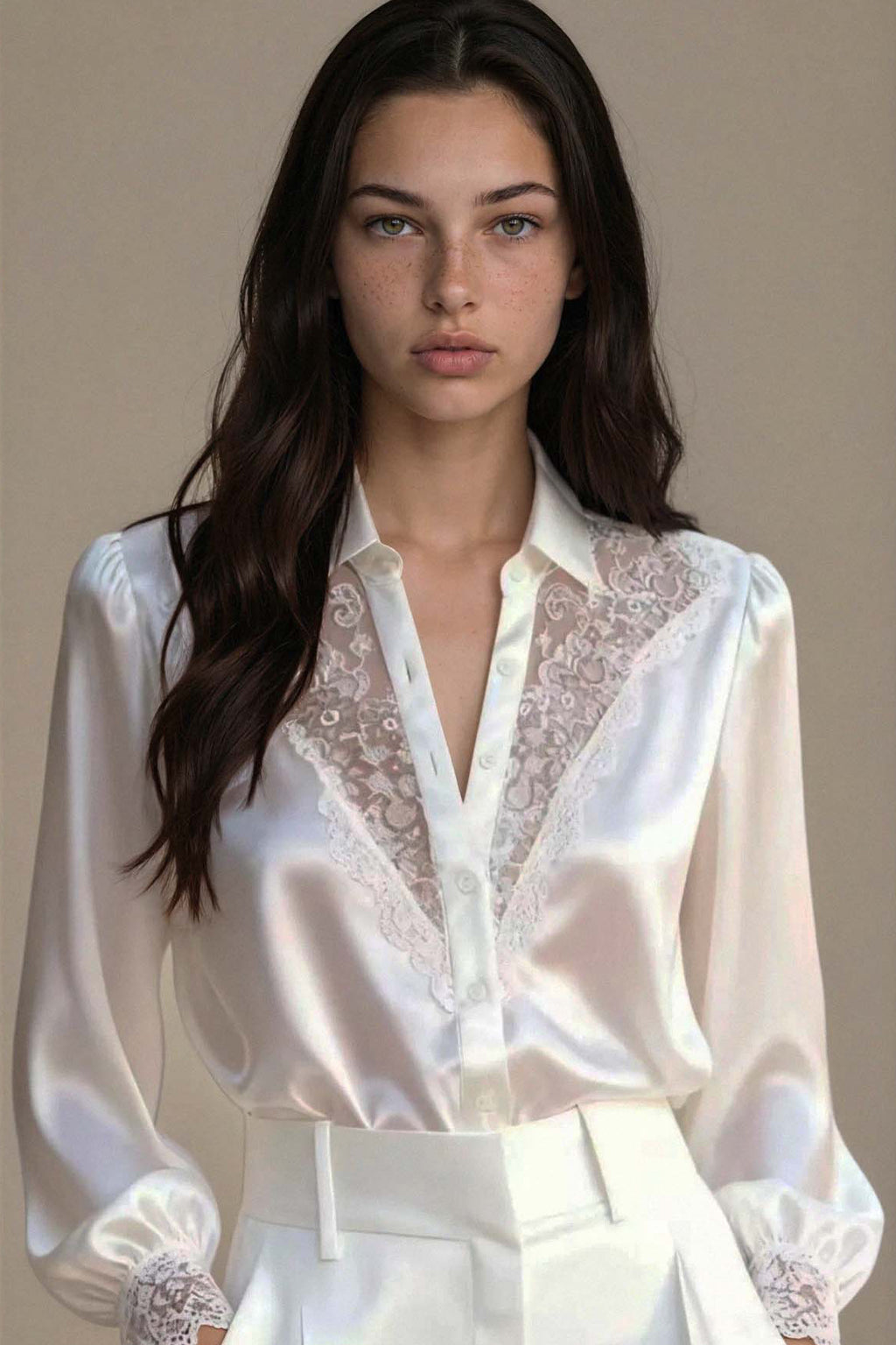 Woman wearing a white blouse with lace details against a neutral background