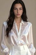 Woman wearing a white blouse with lace details against a neutral background
