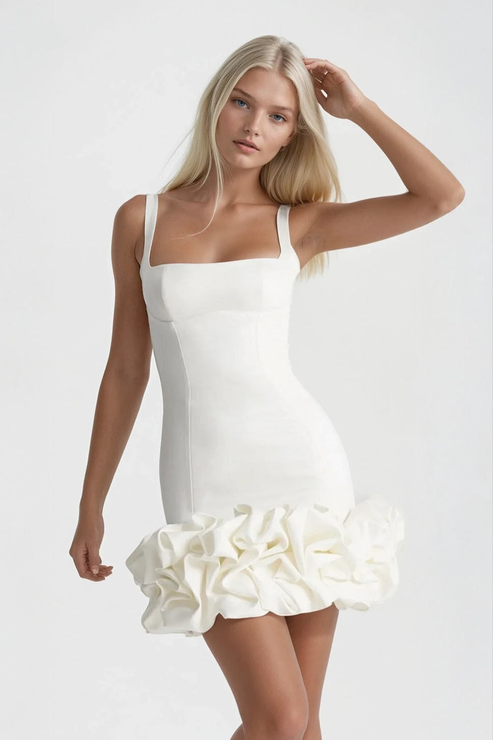Woman wearing a white dress with ruffled skirt on a plain background
