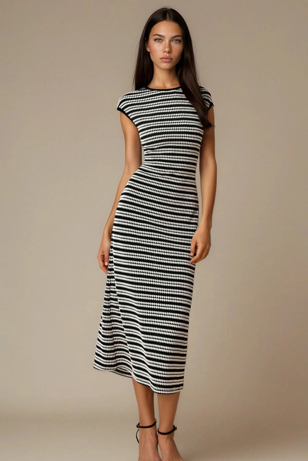 Woman wearing a black and white striped dress against a beige background