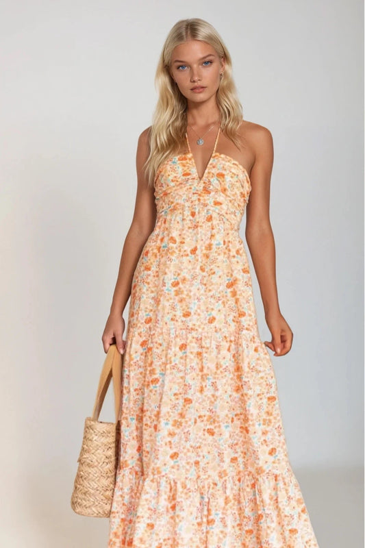 Woman wearing a floral dress holding a straw bag against a plain background