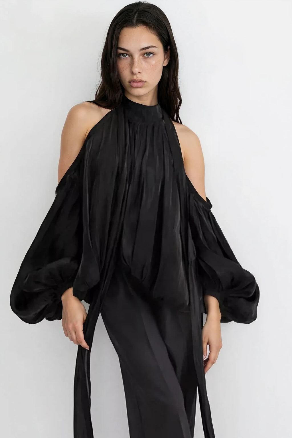 Woman wearing a black off-shoulder top and pants against a white background