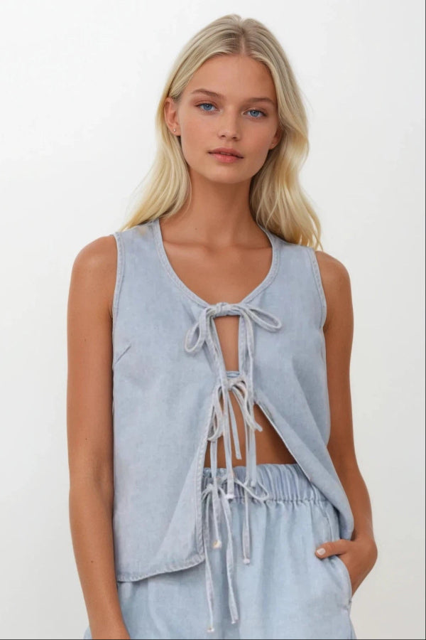 A woman wearing a tied front v-neck vest and matching shorts in a denim material.